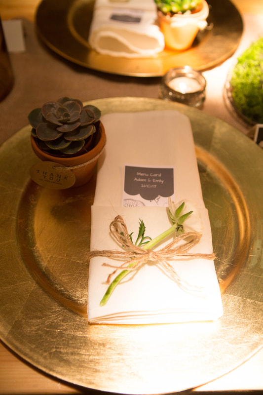 Gold charger plate with white napkin and greenery and succulent favour 