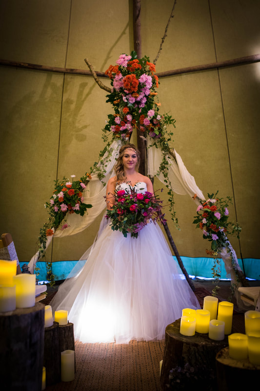 Bride under v arch with pink bouquet