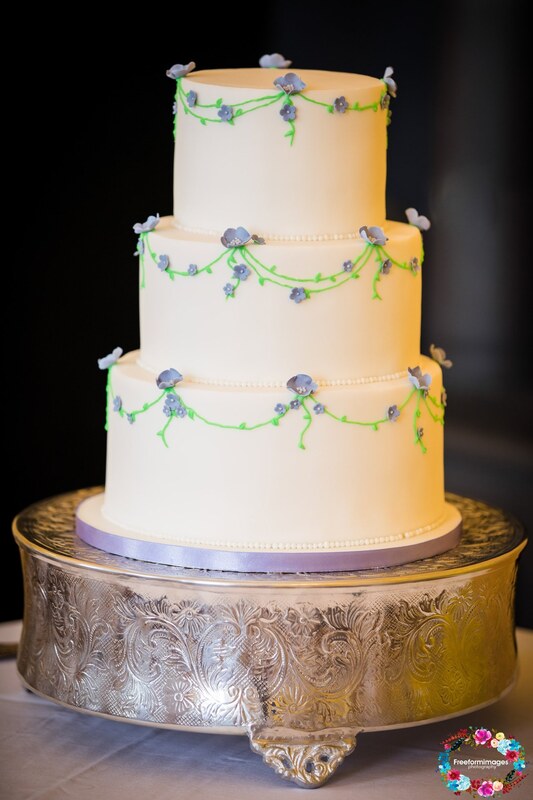 Fondant wedding cake with hand piped vines & small blue flowers