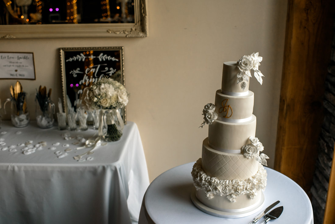 5 tier white wedding cake with white sugar flowers and ruffles