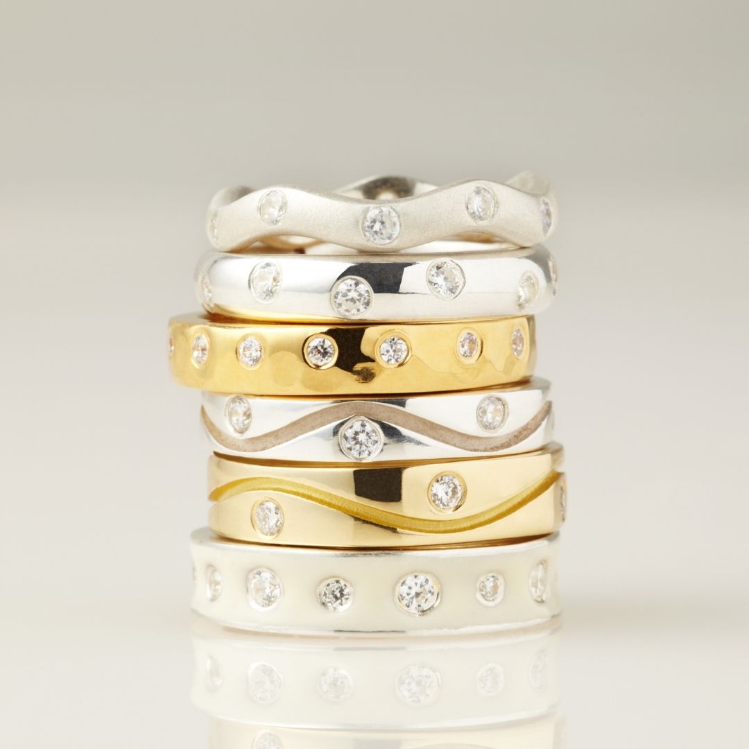 Stack of gold & silver rings with small clear gems 