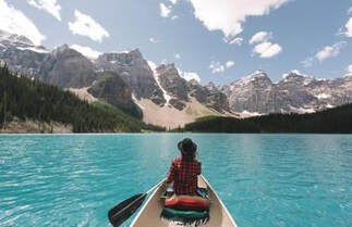 Lady in canoe with mountains in view