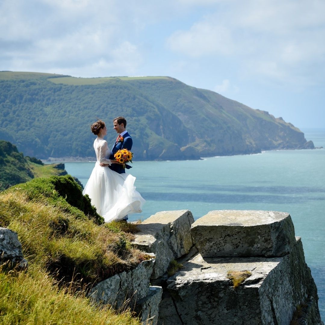 Bride & groom stood on cliff edge with sea in the background